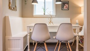 A dining area with a white table, two gray chairs, a white bench, pendant lights, a window with a plant, and a framed picture on the wall. - Urban Farmhouse - 3BR 2.5 BA (5 Beds) Near TG Park & Central to Everything! (St. Louis)