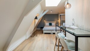 A modern bedroom with a skylight, a bed, bedside table, and a glass dining table with chairs. - Stadsvilla Mout (Schiedam)