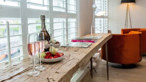 A wooden table with a bottle, glasses, and strawberries. - Stadsvilla Mout (Schiedam)