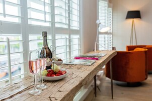 Una mesa de madera con una botella, copas y fresas.