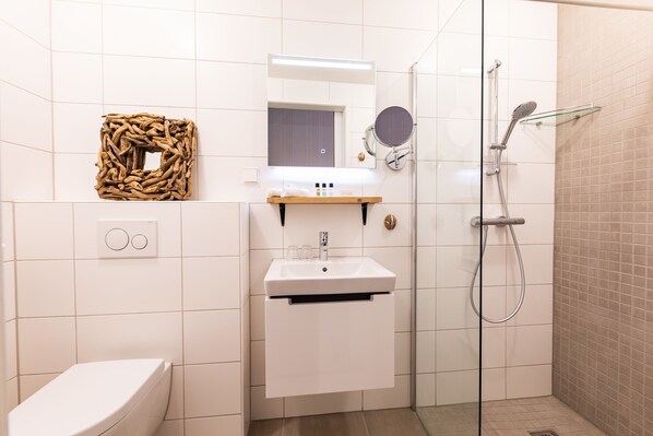 Un baño moderno con inodoro, lavamanos y ducha.