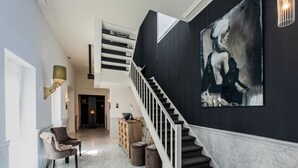 A spacious foyer with a marble floor, a staircase, a modern chair, and a large abstract painting. - Stadsvilla Mout (Schiedam)