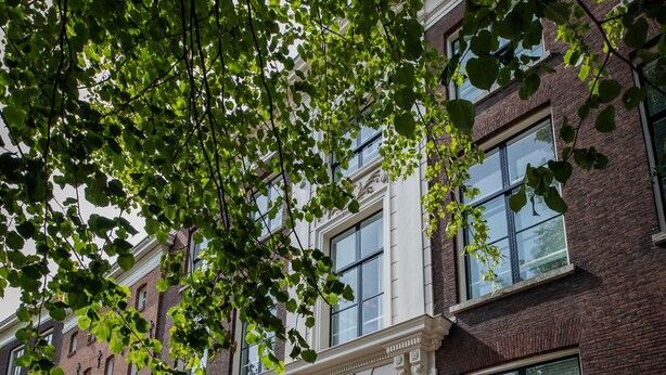 A brick building with large windows and a door with a sign above it. - Stadsvilla Mout (Schiedam)