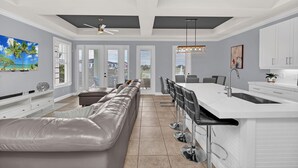 A modern kitchen with a white countertop, a built-in sink, and a bar area with stools.