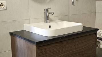 Un bagno con un mobile contenitore in legno, un lavandino bianco e uno specchio rotondo.