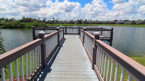 A wooden bridge leading to a body of water with houses in the background. - Brand new private pool with lake view minutes to the parks! (Kissimmee)