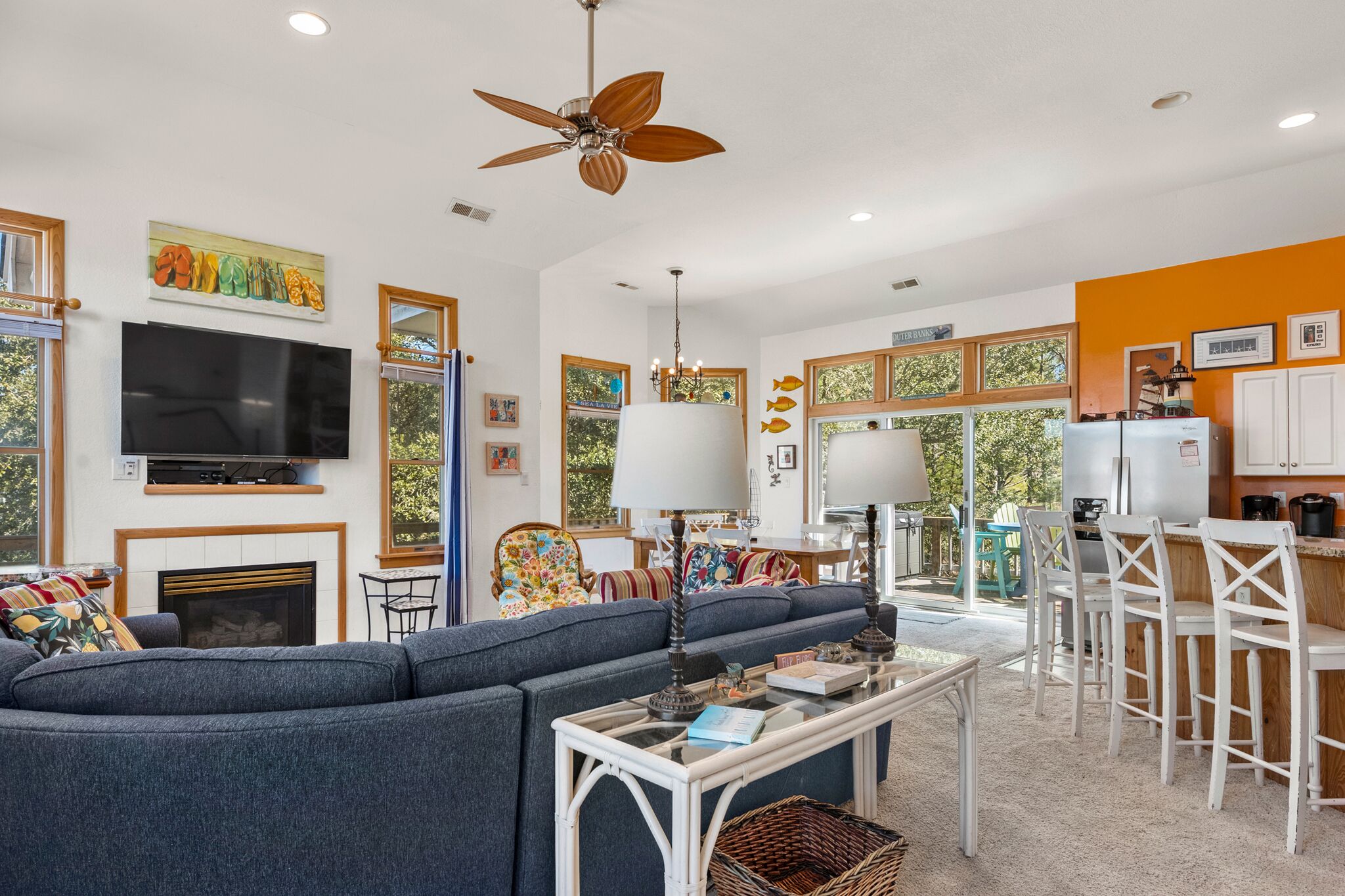 A spacious living room with a large sofa, a television, and a ceiling fan.