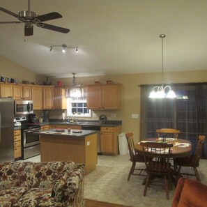 A kitchen with wooden cabinets, a refrigerator, a microwave, and a dining area with a table and chairs.