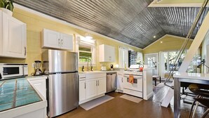 Una cocina con gabinetes blancos, electrodomésticos de acero inoxidable y piso de madera.