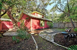 A red house with a yellow roof, surrounded by trees and a wooden fence.