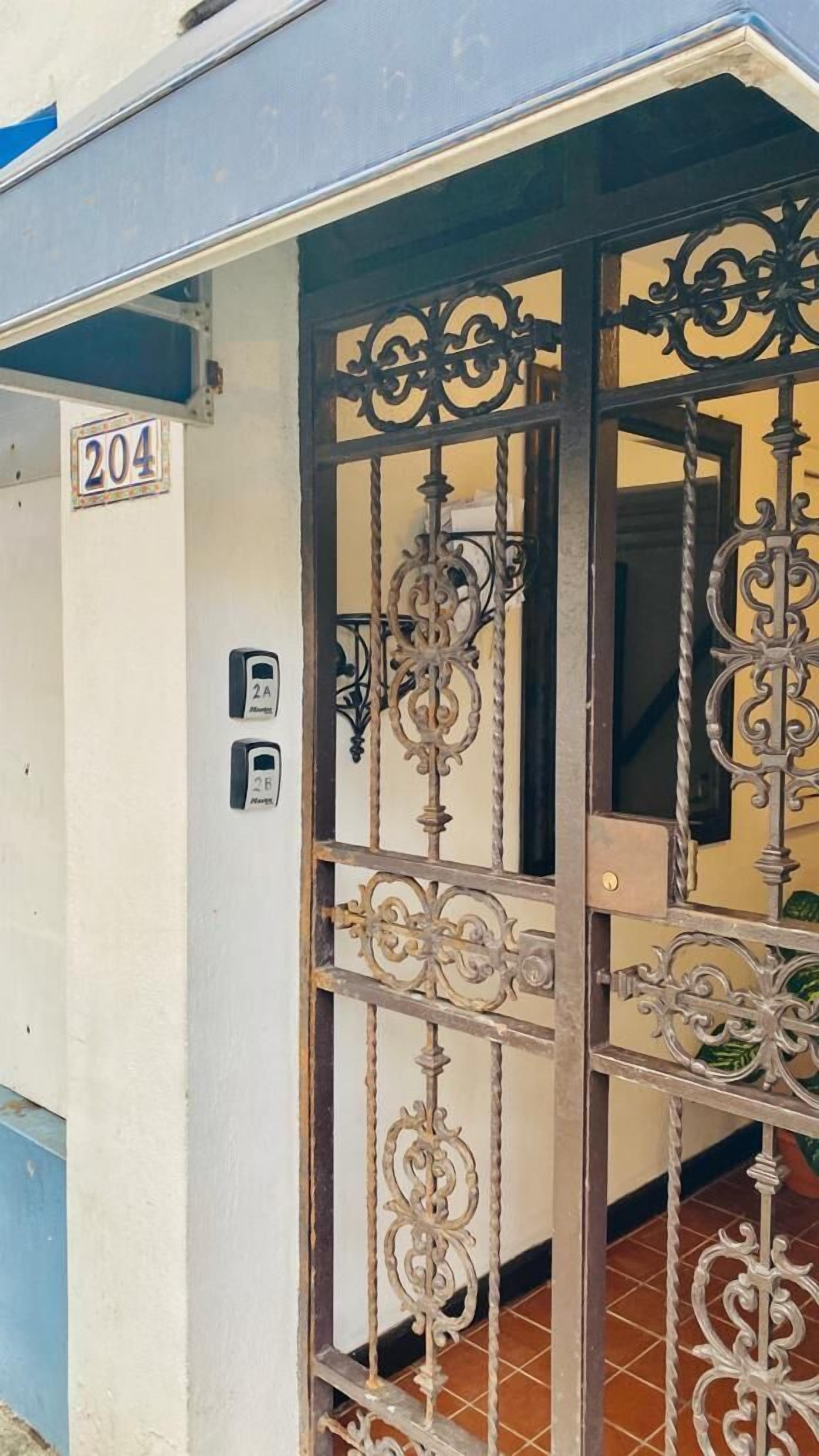 A metal gate with ornate designs, a number '204' sign, and two push buttons labeled '2A' and '2B'.