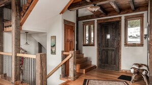 A wooden staircase leading to a second floor, a rustic wooden door, and a view of the outdoors through a window. - Ski In/Ski Out | Hot tub | Mountain View (Big Sky)