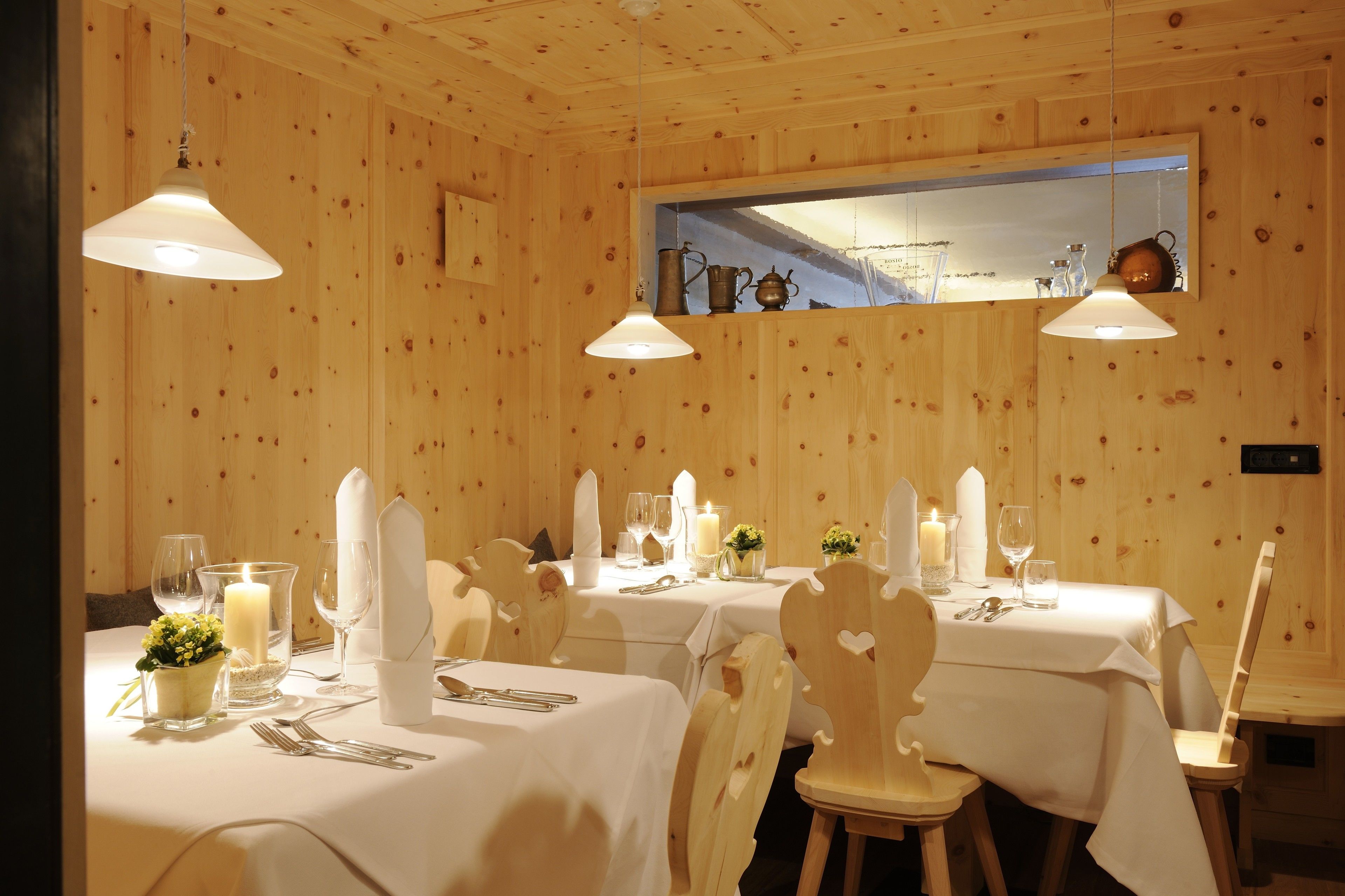 A dining area with wooden walls, white tablecloths, and candle-lit tables.