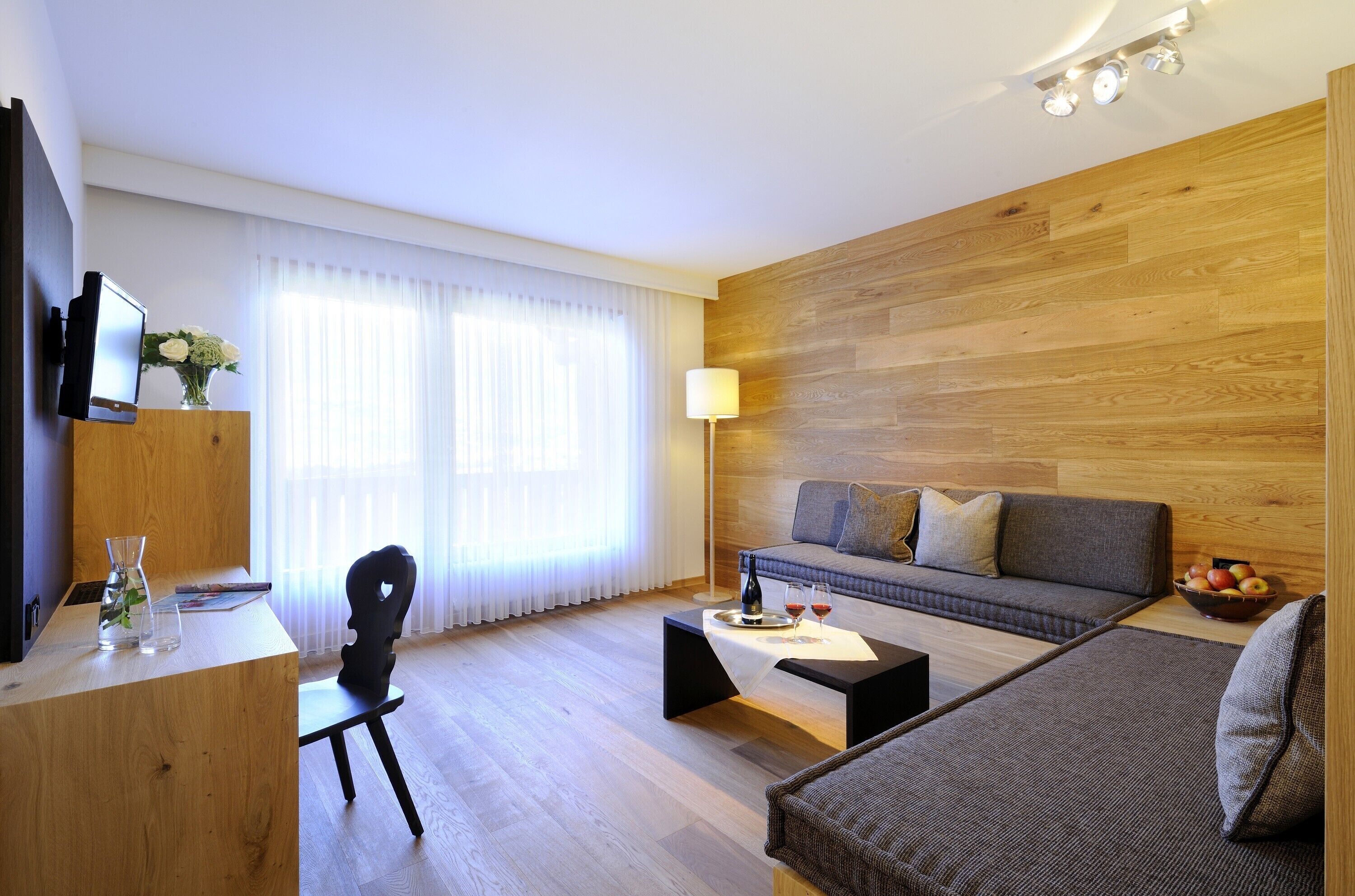 Una sala de estar moderna con piso de madera, un sofá, una mesa de centro, un televisor y una lámpara.