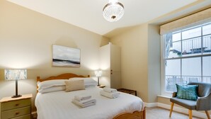 A hotel room with a large bed, bedside lamps, a view of the outside through a window, and a chair by the window. - 2 Bed in Ilfracombe (oc-harbh) (Ilfracombe)