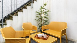 A corner seating area with yellow woven chairs and a matching table, a potted plant, and a tray with cups and a teapot. - 2 Bed in Ilfracombe (oc-harbh) (Ilfracombe)