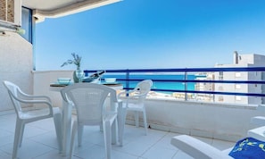 A balcony with white plastic chairs, a small table, and a vase with plants. - Turquesa Beach 310B - Grupo Turis - Calpe, Costa Blanca (Calpe)