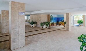 A spacious lobby with a sign indicating the direction to the toilet, tiled flooring, and potted plants. - Turquesa Beach 310B - Grupo Turis - Calpe, Costa Blanca (Calpe)