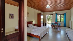 A spacious room with a wooden ceiling, a large bed, a dining table with chairs, and a view through a window. - Heliopetra studios, small village close to beaches (Vamos)
