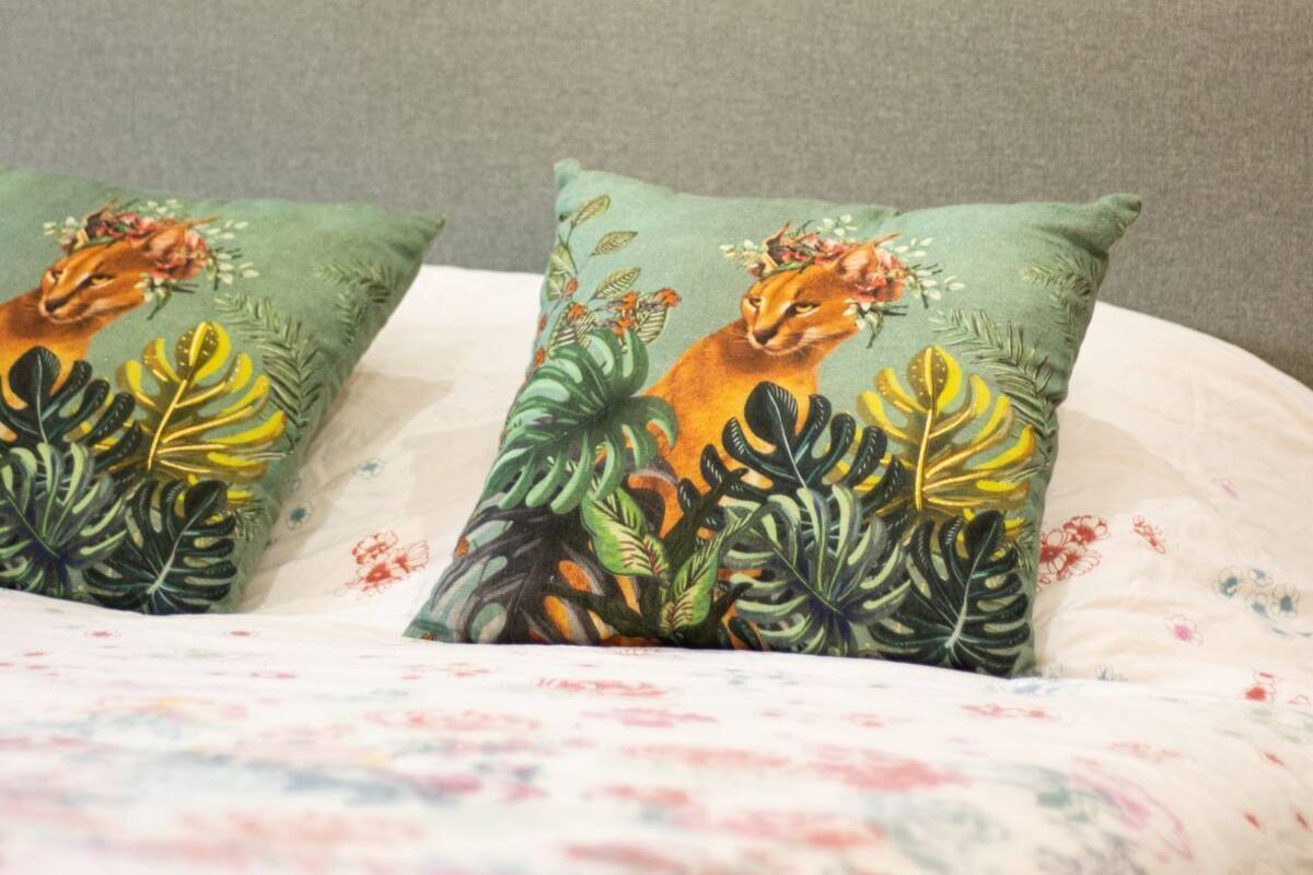 A bed with a floral-patterned bedspread and two pillows with a nature-themed design.