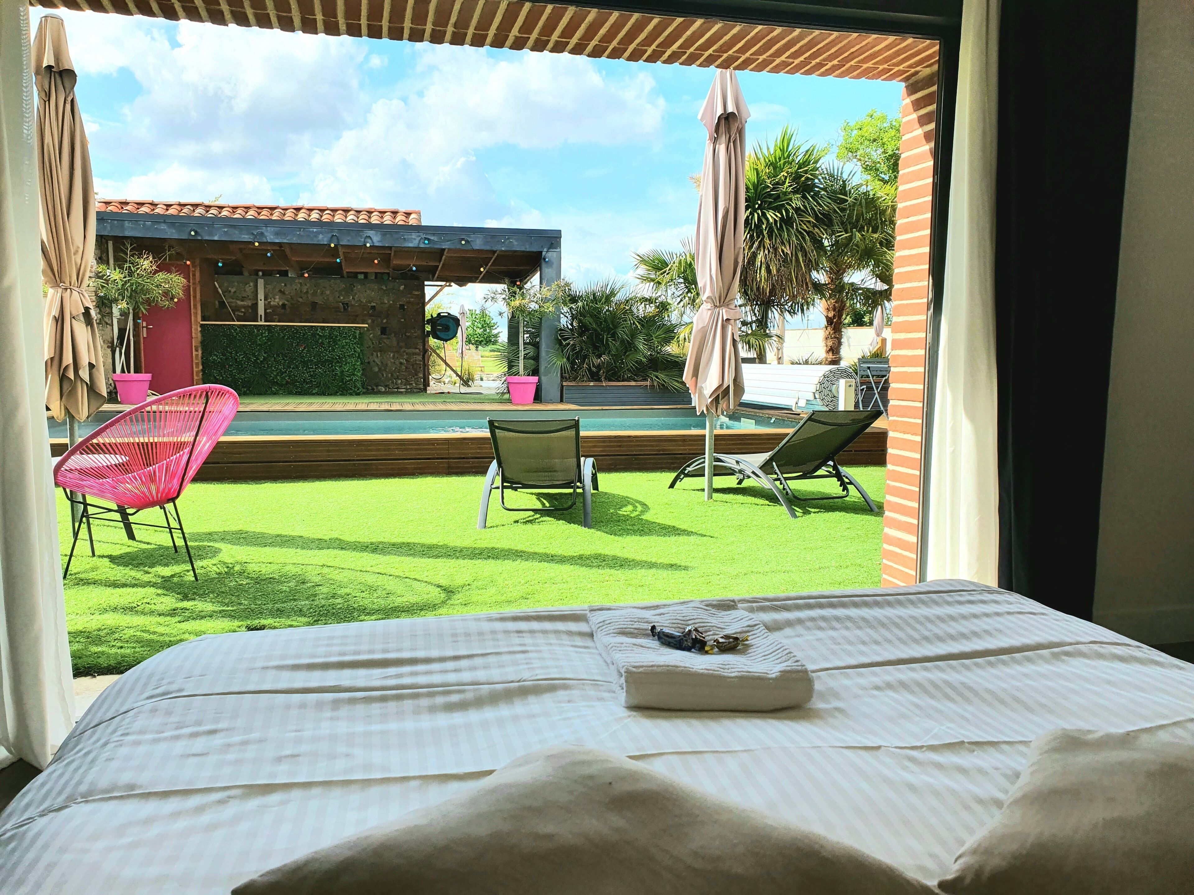 Ein Zimmer mit Bett, Blick auf einen Pool und Sitzgelegenheit im Freien.