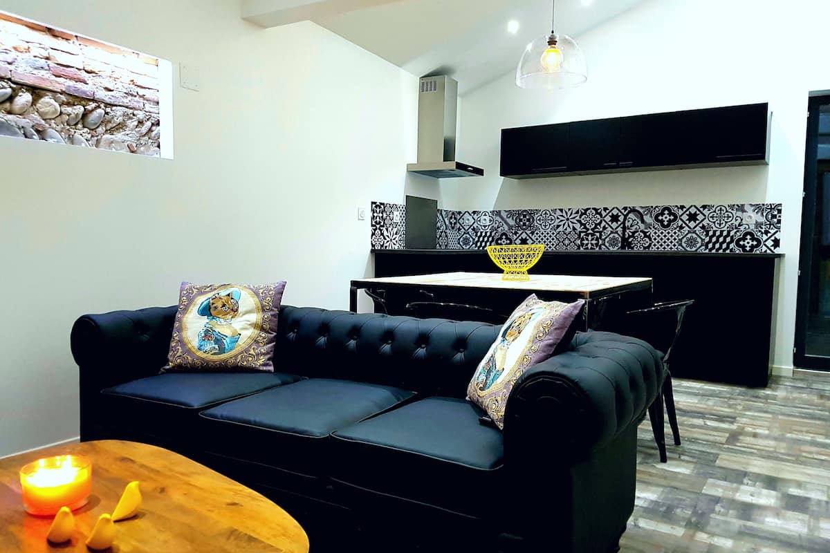 A modern living room with a black sofa, a wooden coffee table, and a lit candle.