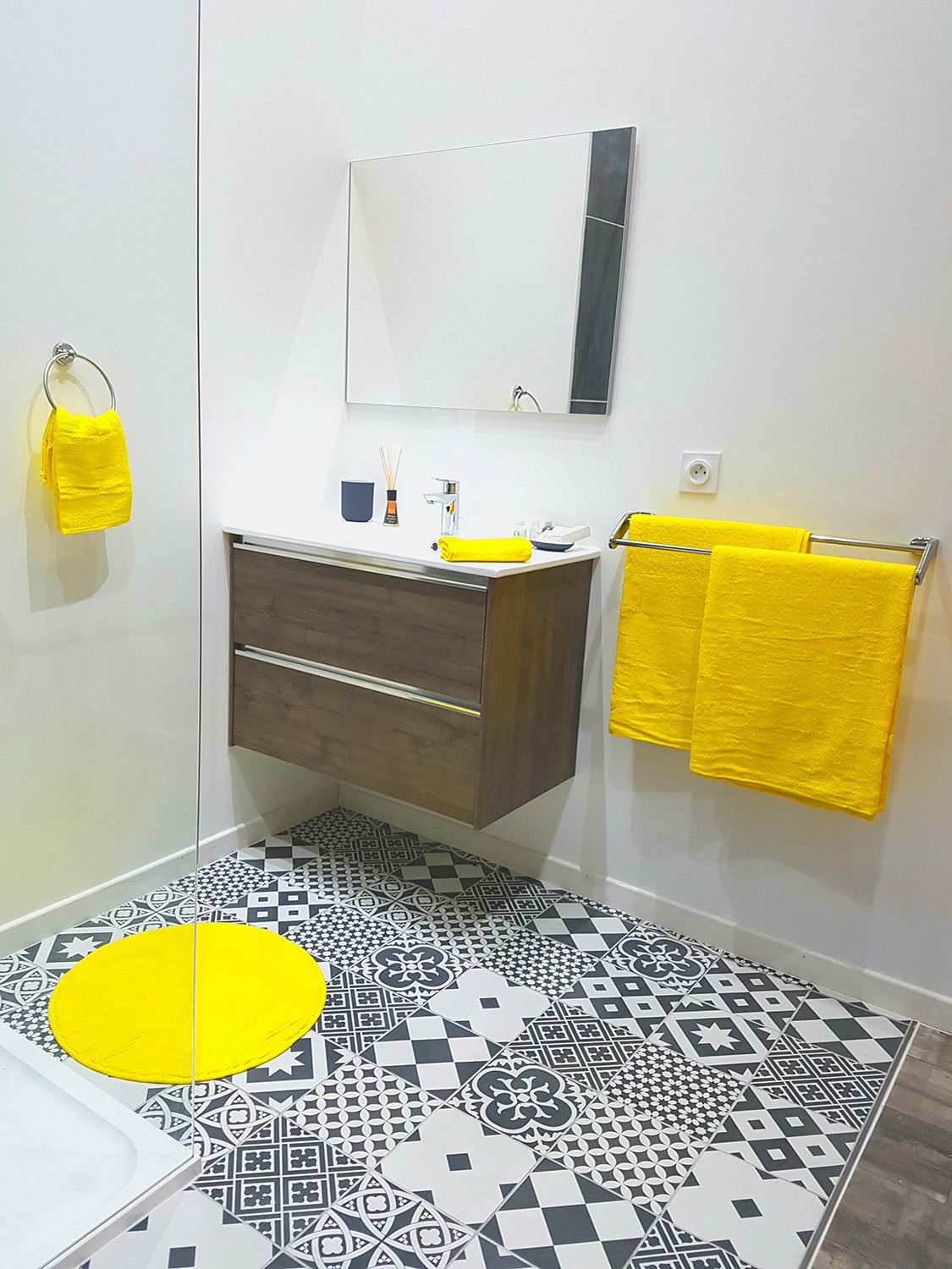 A bathroom with a white sink, dark wooden vanity, a mirror, and two yellow towels on a rack.