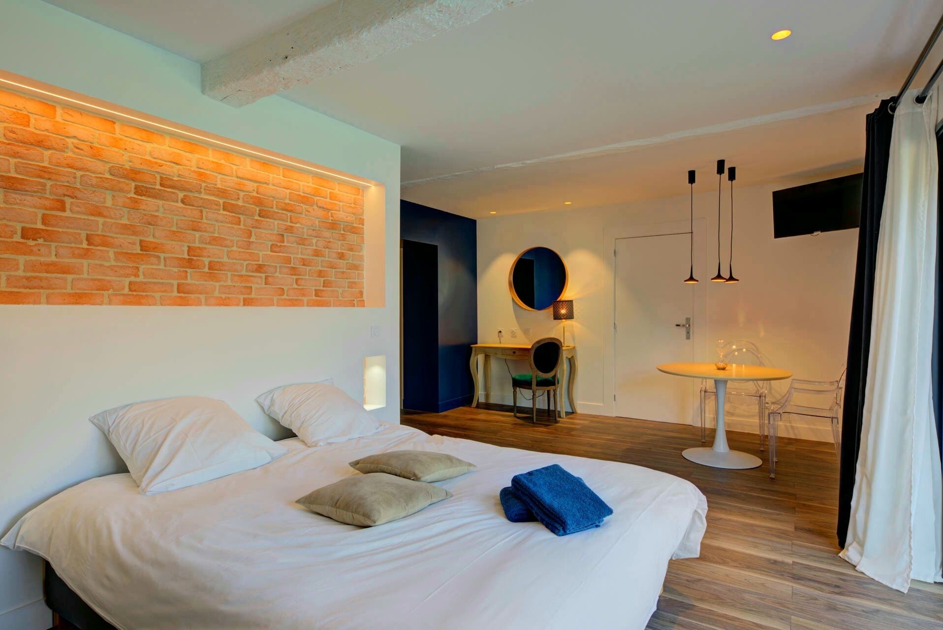 Una habitación de hotel moderna con una cama grande, un escritorio y una mesita redonda.