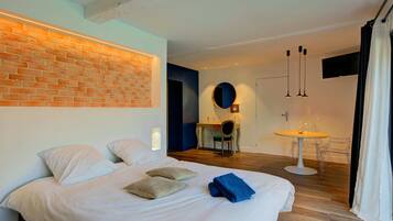 Una habitación de hotel moderna con una cama grande, un escritorio y una mesita redonda.