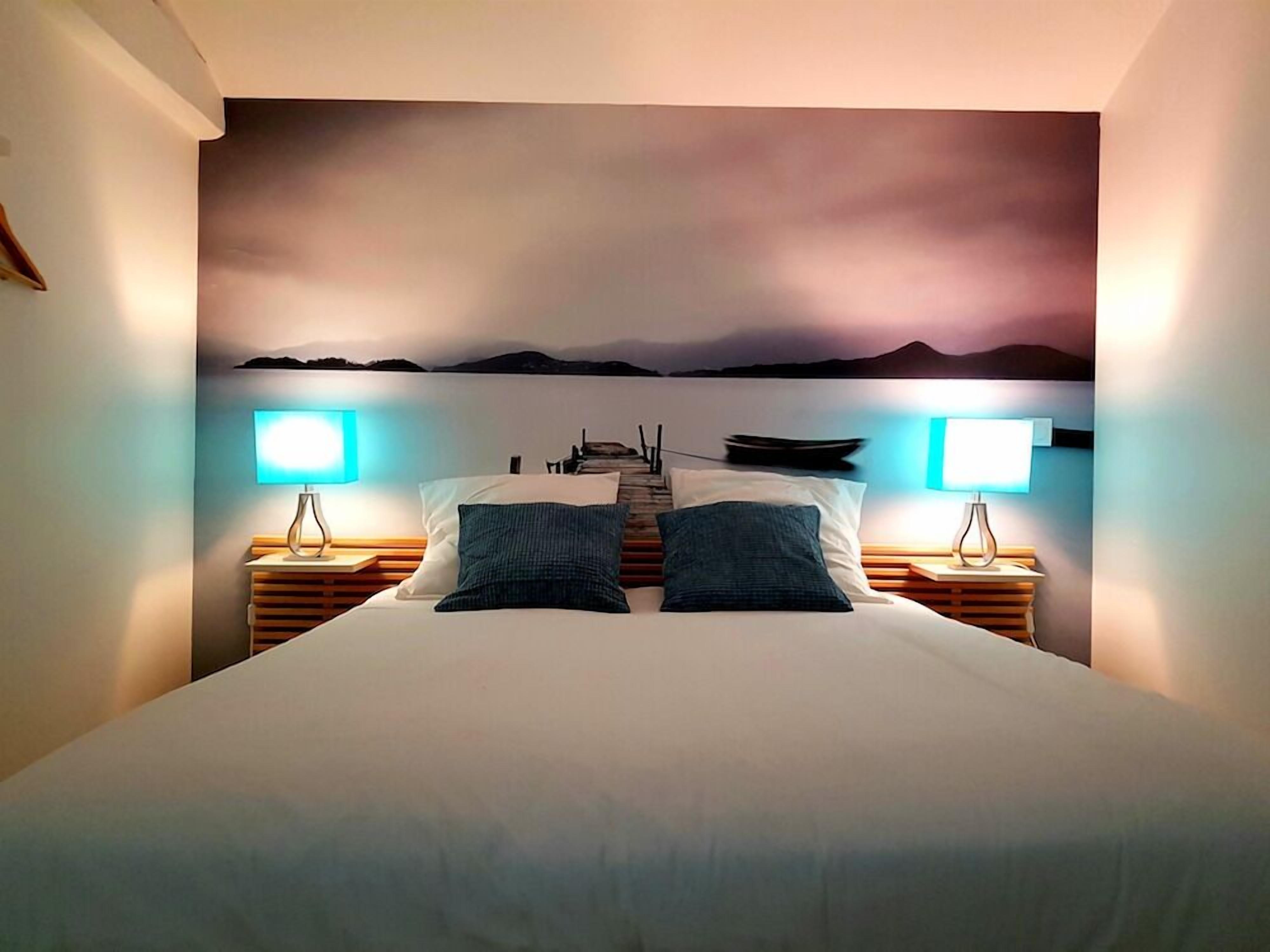A bedroom with a bed centered in the room, flanked by two bedside tables with lamps.