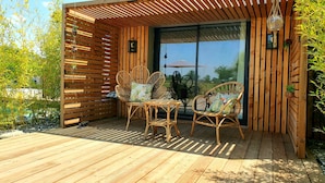 A wooden deck with wicker chairs and a table, a wooden pergola, and a glass door leading to a garden. - Les Granges de Jules (Lafitte-Vigordanne)