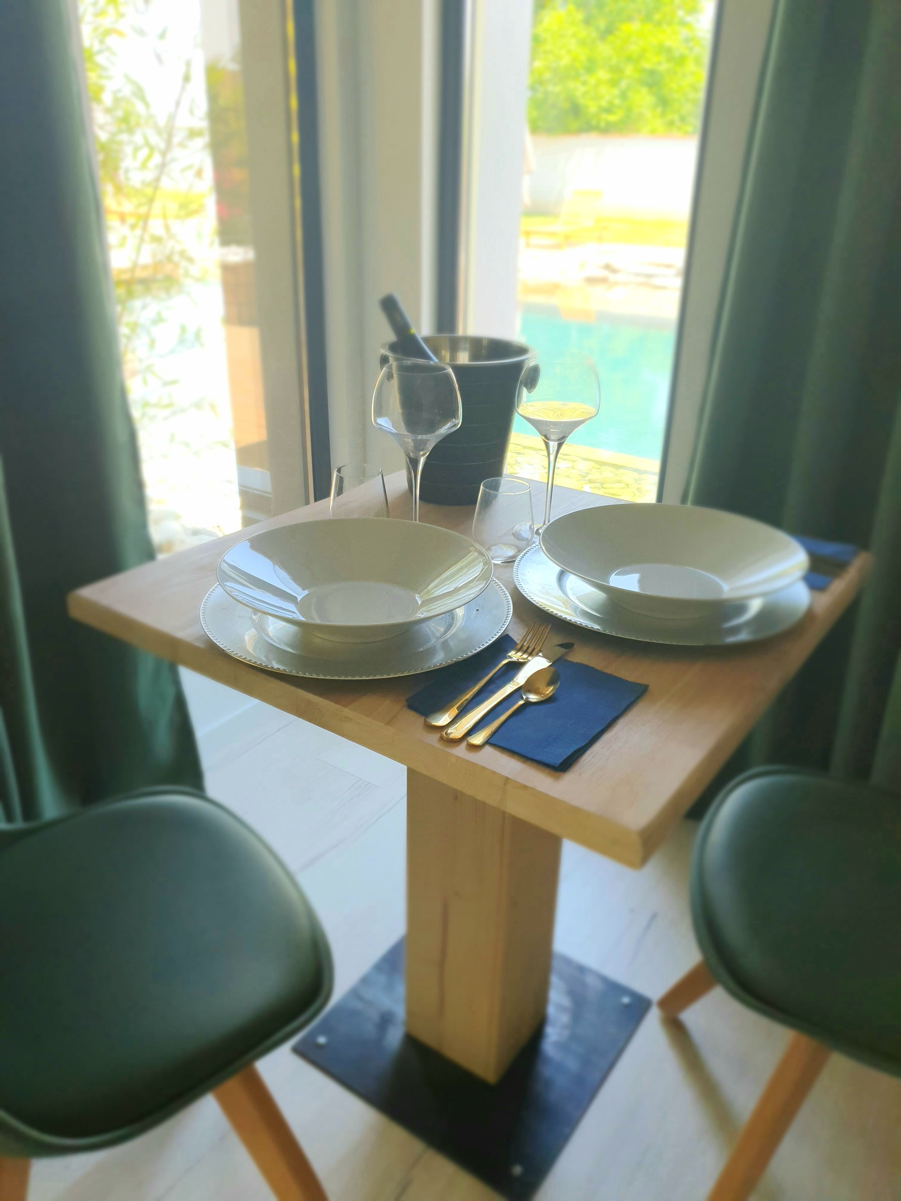 Mesa de jantar com pratos, talheres e uma taça de vinho.