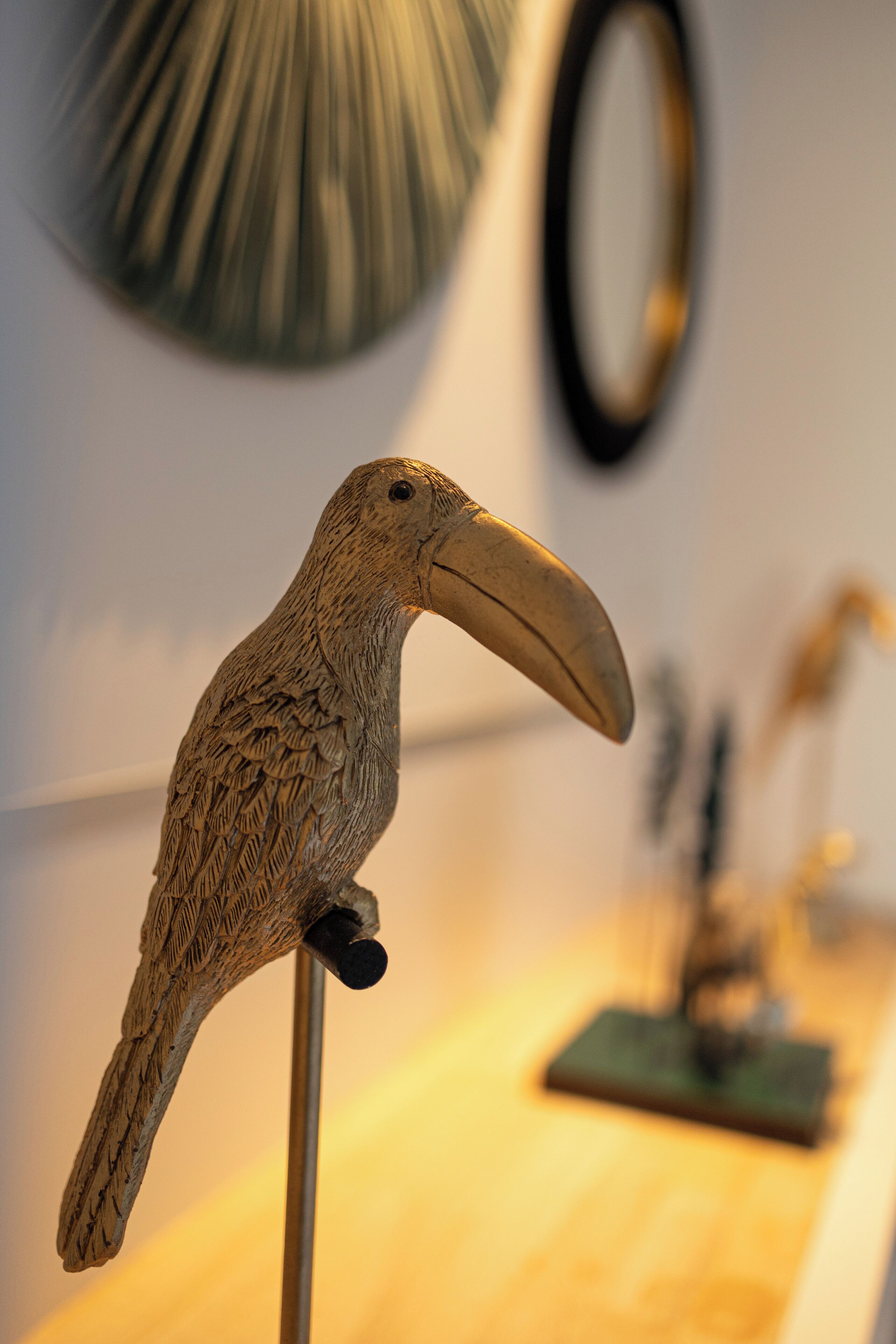 A wooden bird sculpture on a stand.