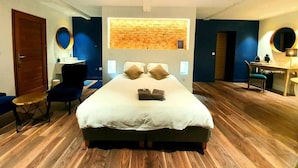 A modern hotel room with a large bed, a desk, and a seating area. - Les Granges de Jules (Lafitte-Vigordanne)