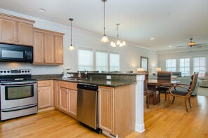 Enjoy cooking in this well-equipped kitchen with a stainless steel oven and dishwasher, adjacent to a dining area with a wooden table.