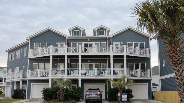 A multi-story residential building with balconies, a garage, and a 'For Sale' sign. - 4 BR Corner Unit Oceanfront Steps to it all! (Kure Beach)