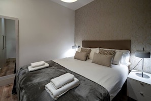 A hotel room with a bed, bedside lamps, a nightstand, and a wardrobe.