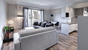 Ein modernes Apartment mit grauem Sofa, Esstisch und Küchenbereich.