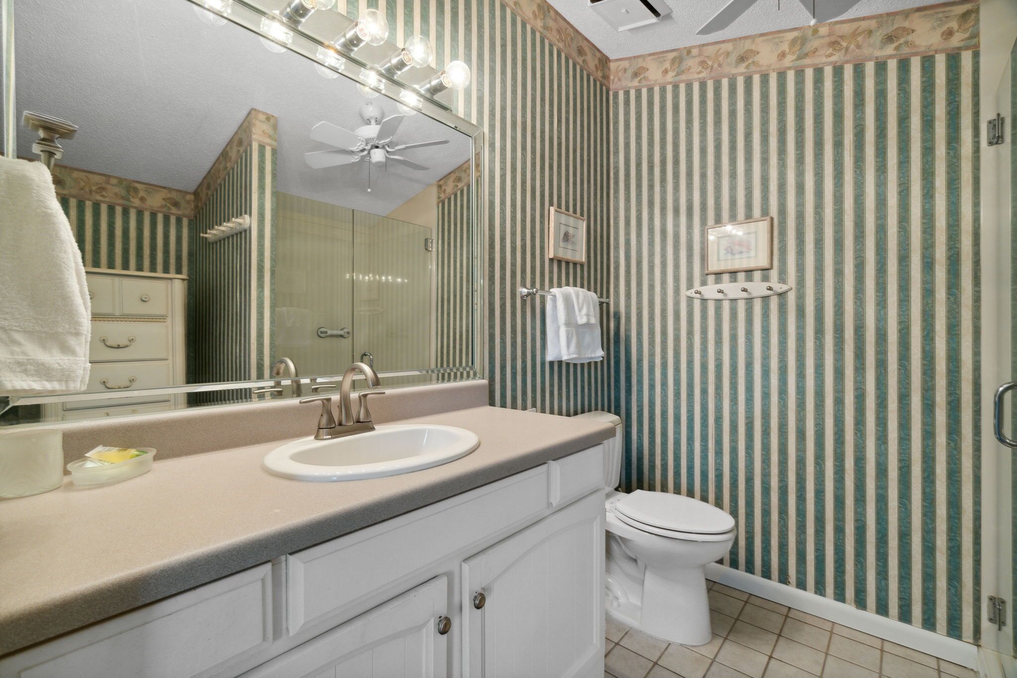 A bathroom with a vanity, sink, mirror, and toilet.