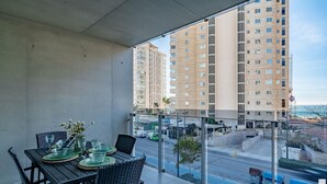 A balcony with a dining table set, overlooking a street with buildings and a clear sky. - El Mirador de Calpe 2E - Grupo Turis - Calpe, Costa Blanca (Calpe)