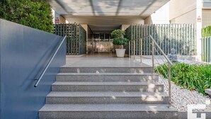 A modern building entrance with a covered staircase, a large potted plant, and a Buddha statue. - El Mirador de Calpe 2E - Grupo Turis - Calpe, Costa Blanca (Calpe)