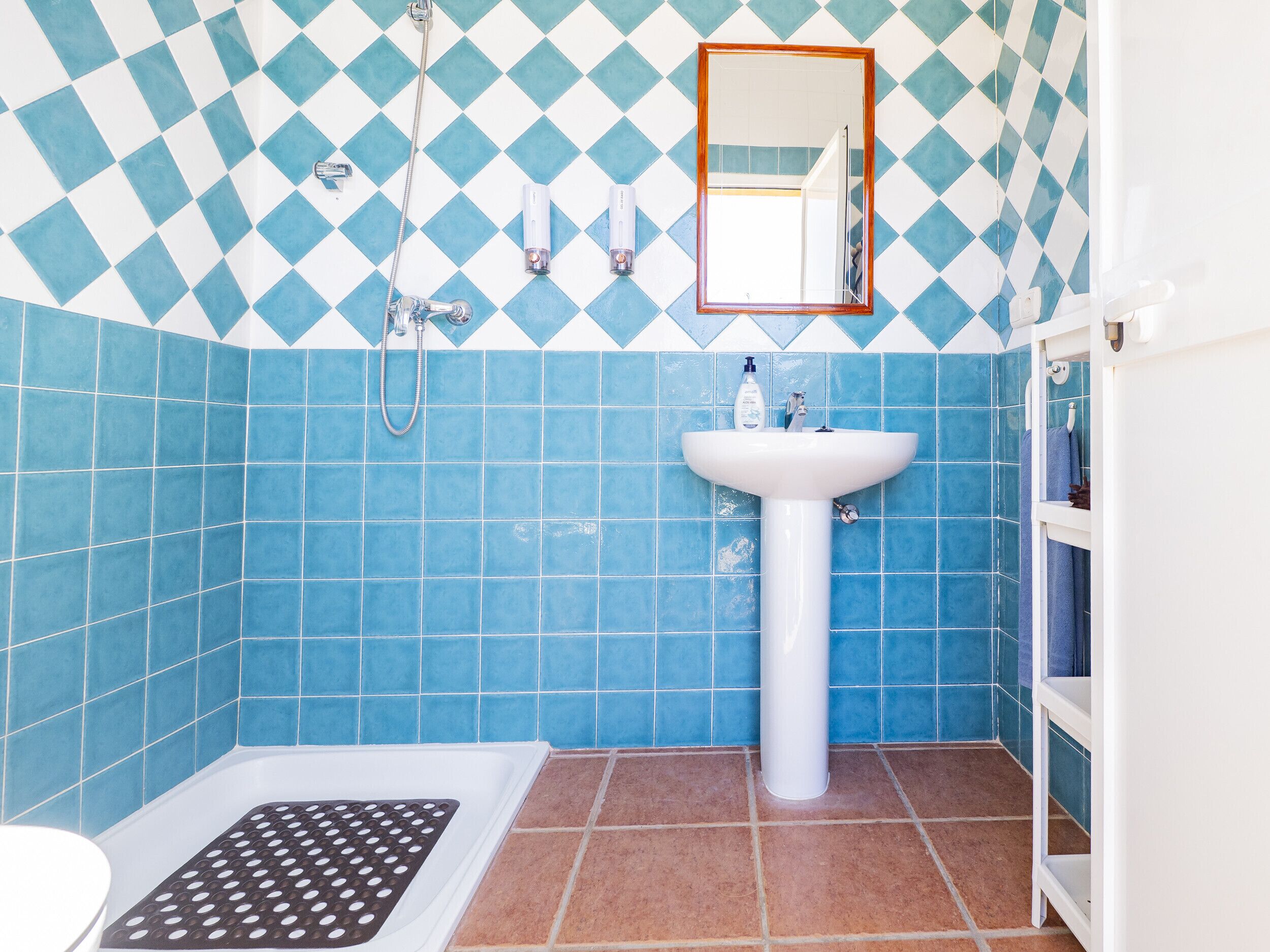 A bathroom with blue and white checkered tiles, a white sink, and a shower.