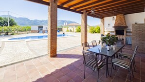 Un patio cubierto con piscina, mobiliario exterior y chimenea de ladrillo.