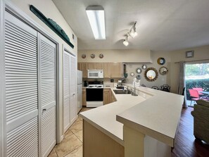 A compact kitchen with a microwave, stove, and sink. There is a dining area with a table and chairs.