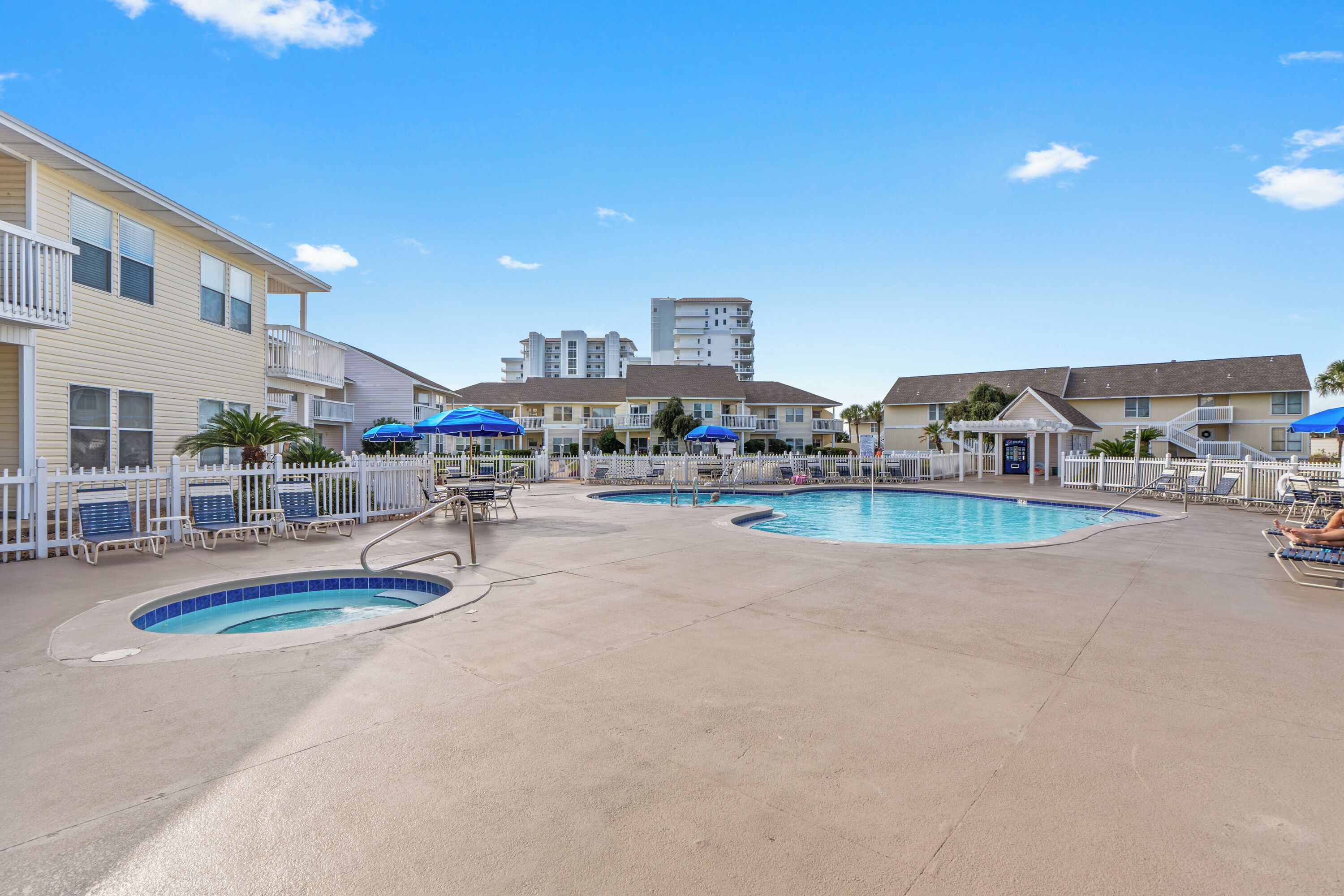 A hotel with multiple swimming pools, lounge chairs, and umbrellas.