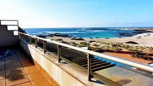 Un balcon avec vue sur l’océan et la plage.