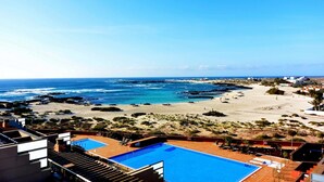 Un espace piscine offrant une vue sur l’océan et la plage.
