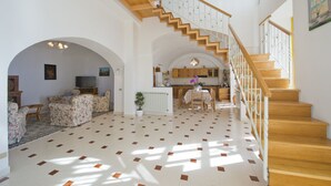 Amplia sala de estar con una escalera que conduce a la cocina.