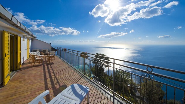 Balcón con mobiliario exterior con vistas a un paisaje marino.