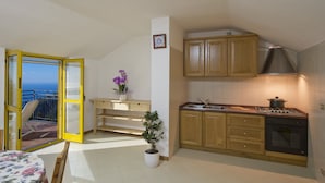 Cocina compacta con armarios de madera, estufa y lavamanos. Incluye un balcón con vistas.